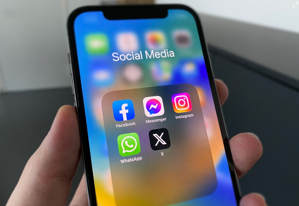 Smartphone screen showing social media apps Facebook, Messenger, Instagram, WhatsApp, and X
