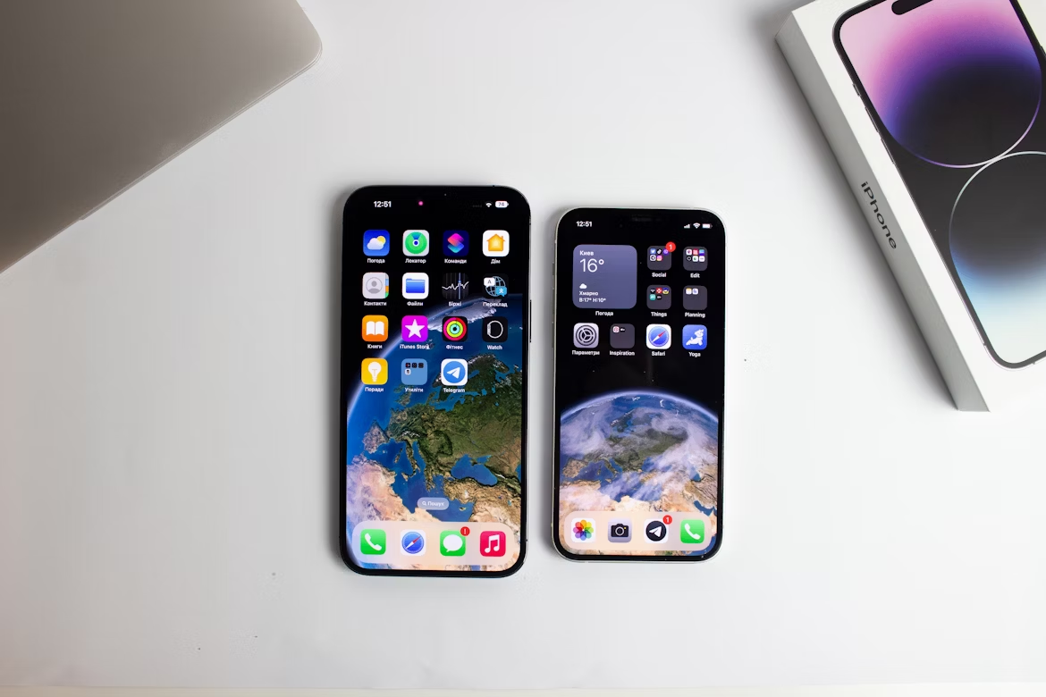 Two iPhones side by side on a white desk with apps displayed