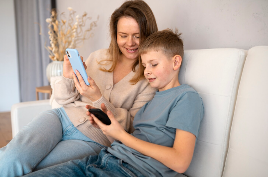 Smiling mother learning from her son as he explains how to use a smartphone